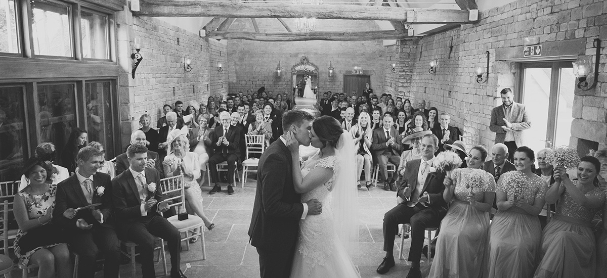 Guests smile and clap as the newlyweds kiss after saying their wedding vows – wedding ceremony